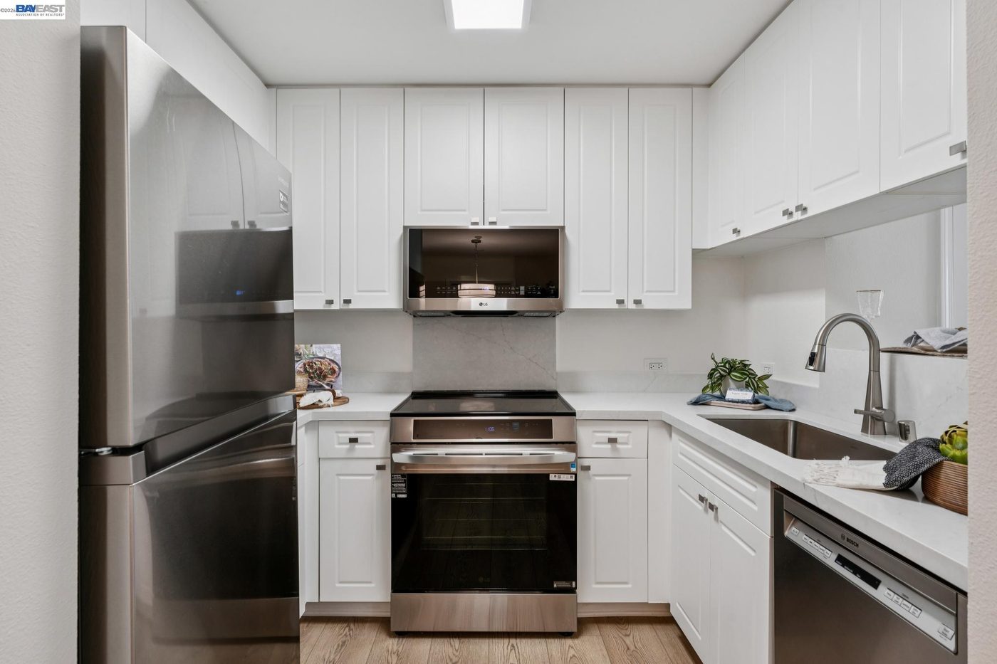 Bright white kitchen with stainless steel appliances and wood floor