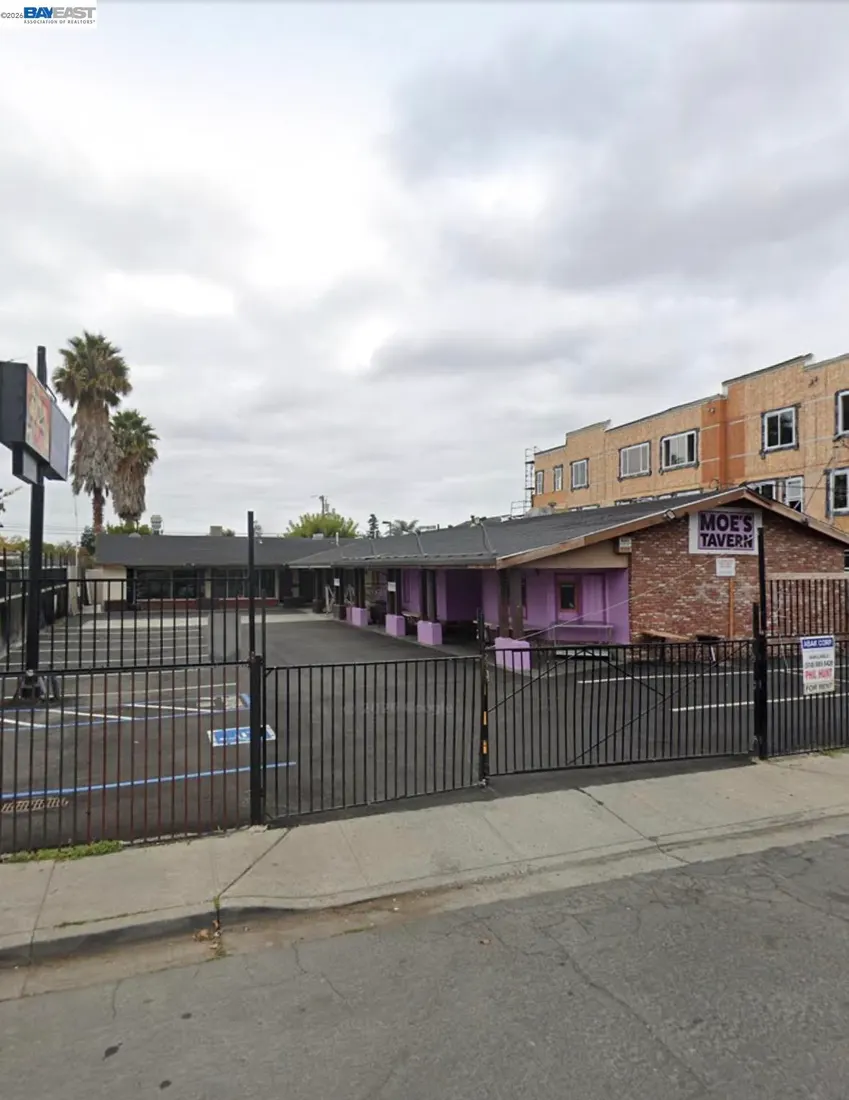 Purple commercial building with Moe's Tavern sign behind black fence