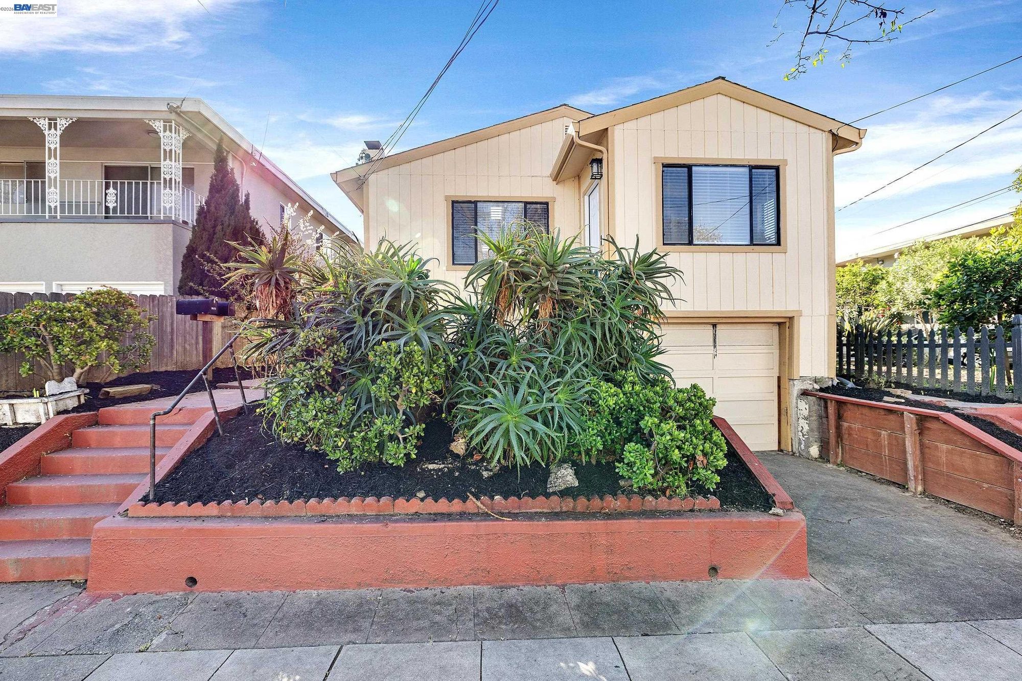 Tan house with raised planter of succulents and steps to entry